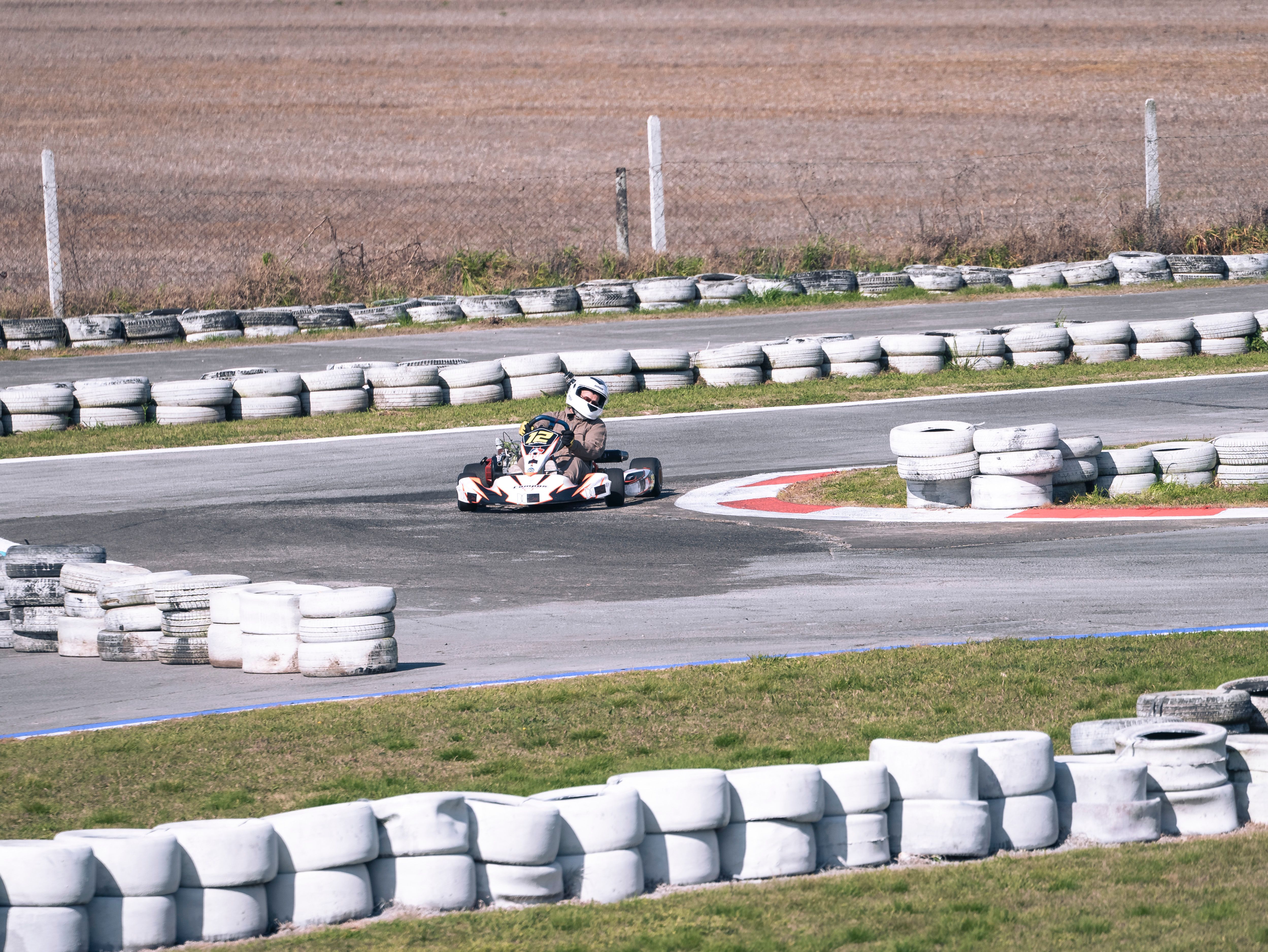 Go-kart drivers racing around an outdoor circuit bend.